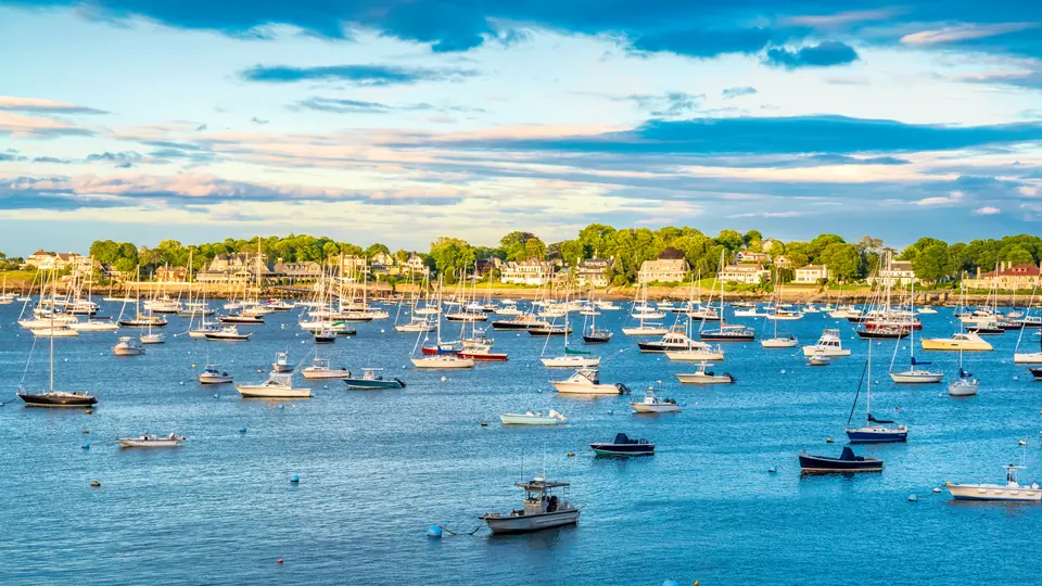 North Shore harbor with moored boats and shoreline homes beyond.